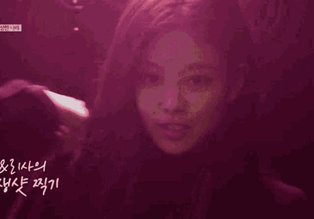 a woman in a dark room with a purple light behind her