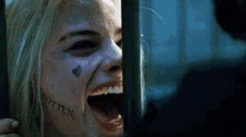 a woman with a tattoo on her face is screaming while holding a sword .