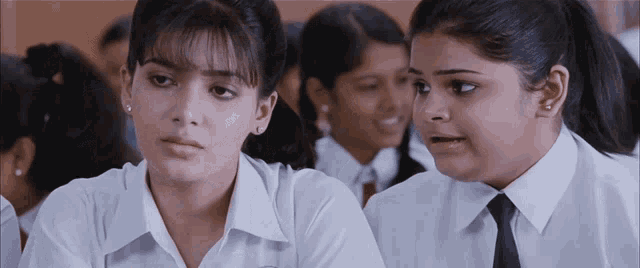 two girls are sitting in a classroom and one is making a funny face