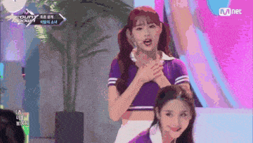 a girl in a purple shirt is standing on a stage with her hands on her chest