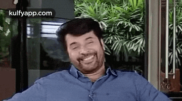 a man in a blue shirt is smiling and making a funny face .