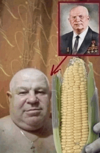 a man is holding a corn on the cob in front of a picture of a man in a suit