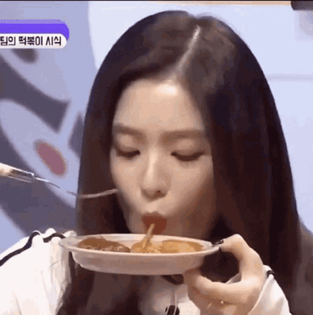 a woman is eating a plate of food with a fork and spoon .