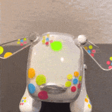 a white toy dog with colorful polka dots on its body