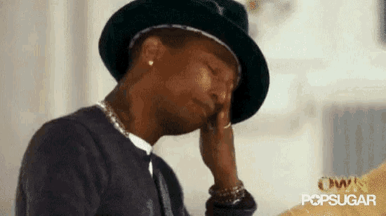 a man wearing a hat and a necklace is rubbing his forehead .