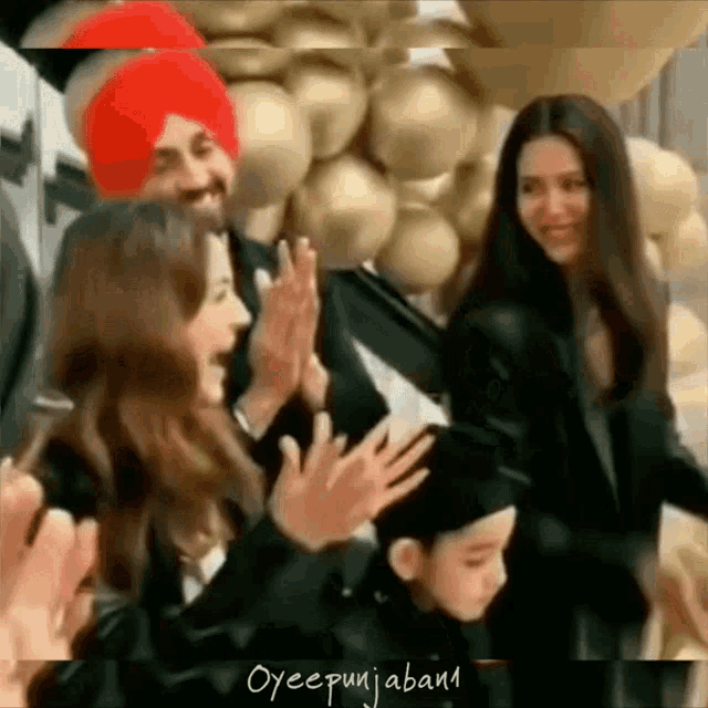 a group of people are standing in front of a wall of balloons .