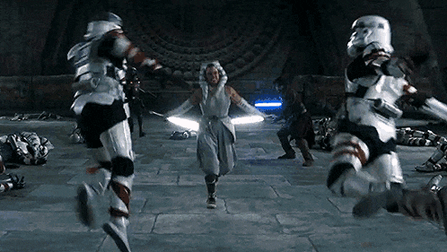 a group of stormtroopers are running towards a woman with lightsabers in a room .