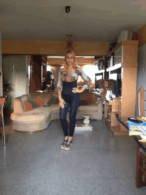 a woman stands in a living room in front of a couch and television