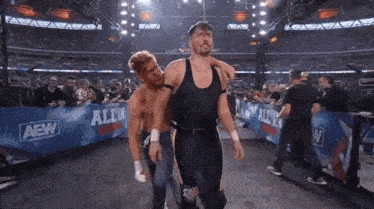 a wrestler is carrying another wrestler on his shoulders in a ring .