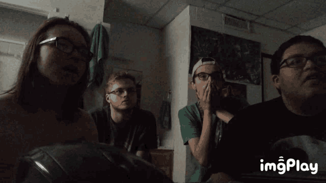 a group of people are sitting in a dark room with a gif that says imgplay