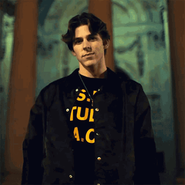 a young man wearing a black jacket and a t-shirt that says a.c.