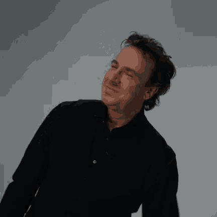 a man in a black shirt is smiling while dancing