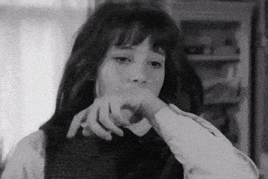 a black and white photo of a woman with her hand on her face .