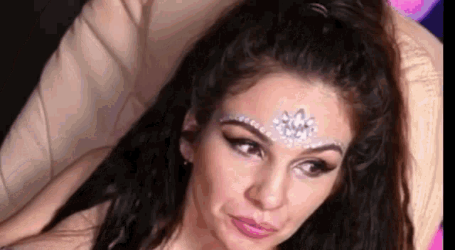 a close up of a woman 's face with a crown on her forehead .