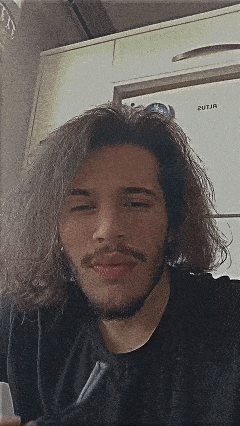 a man with long hair and a beard is wearing a black shirt .