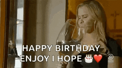 a woman is drinking a glass of wine and saying happy birthday