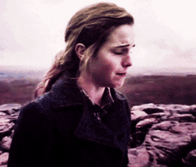 a woman in a black coat is standing in front of a mountain