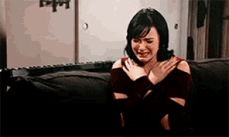 a woman sitting on a couch with her hands on her chest