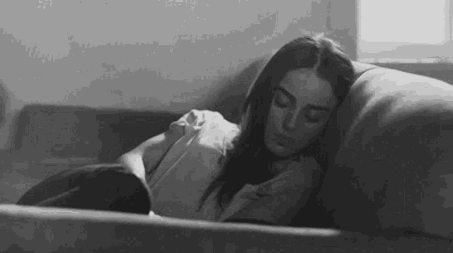 a woman is sleeping on a couch with her head on the pillow .