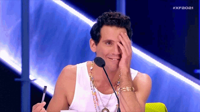 a man covering his face with his hand while sitting in front of a microphone with the hashtag #xf2021