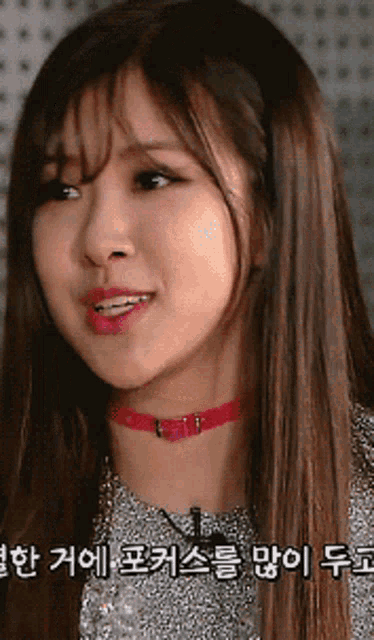 a close up of a woman wearing a red choker with korean writing on it