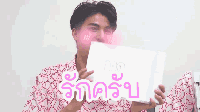 a man is holding a sign that says `` i love you '' in a foreign language .