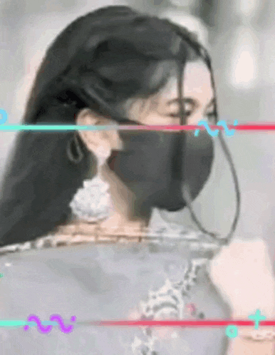 a woman wearing a black mask and earrings is standing in a blurry photo .