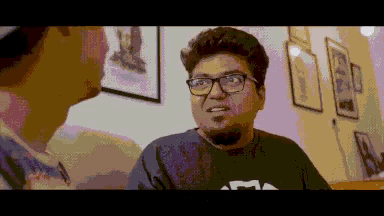 a pixelated image of a man wearing glasses and a black shirt that says m