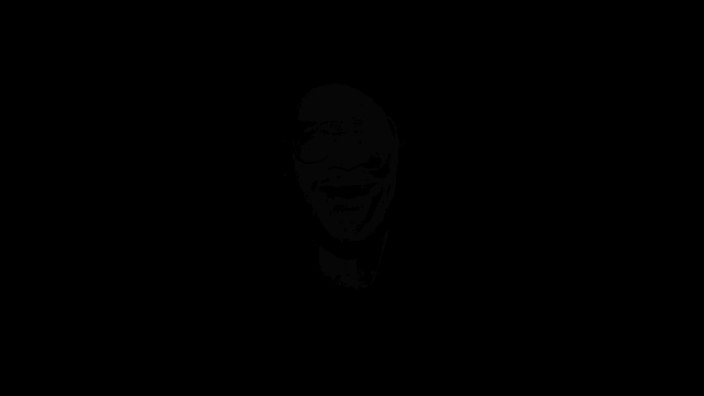 a man with glasses is making a funny face in the dark .