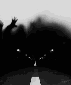 a black and white photo of a person 's hands reaching up in the dark