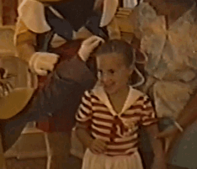 a man in a mickey mouse costume is standing next to a little girl in a striped shirt .