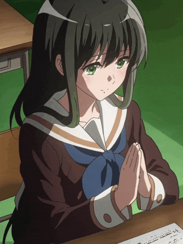 a girl sitting at a desk with her hands folded