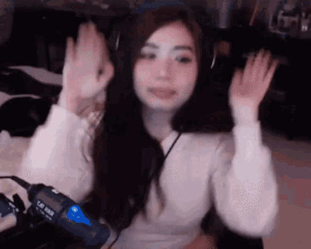 a woman wearing headphones is waving her hands in front of a microphone .