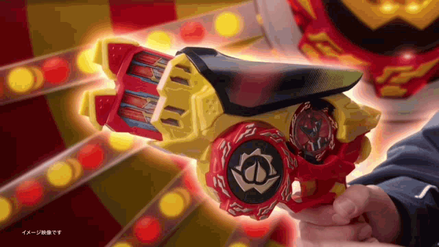 a person is holding a red and yellow toy gun with a chinese symbol on it