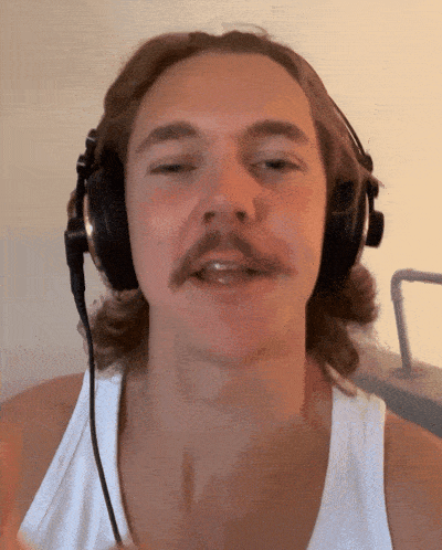 a man with a mustache wearing headphones looks at the camera