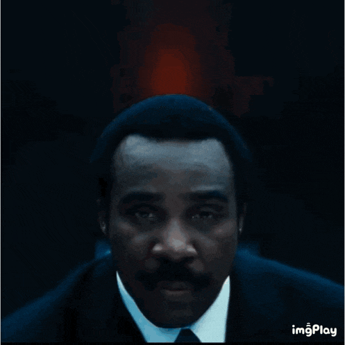 a man in a suit and tie has a blue lanyard around his neck that says imgplay
