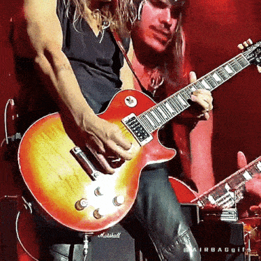 a man playing a guitar with a marshall amp in the background