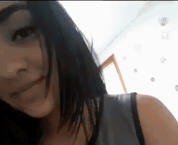 a close up of a woman 's face with a gray tank top on