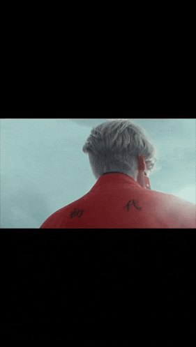 a man with a tattoo on his back wearing a red shirt .