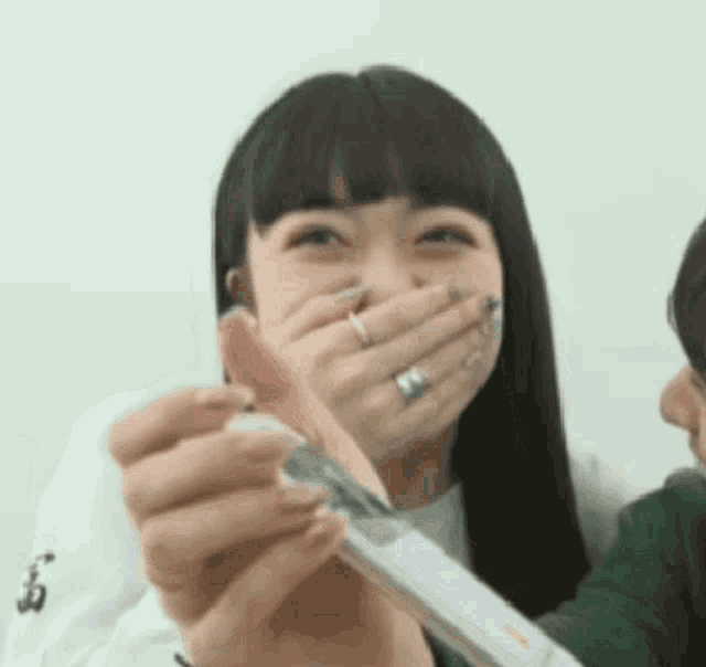 a woman is covering her mouth while holding a pair of scissors in her hand .