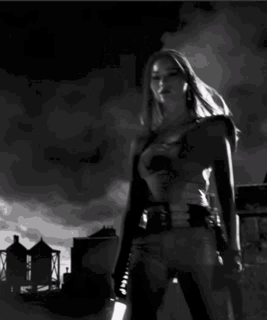 a black and white photo of a woman holding a sword and a gun
