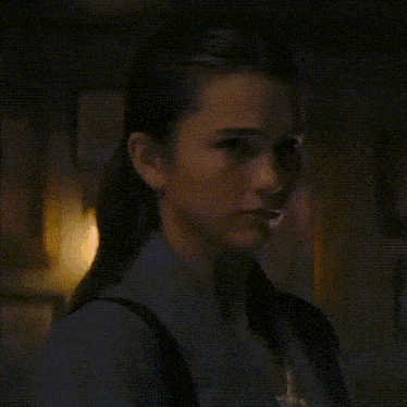 a woman is standing in a dark room with a backpack on her back .