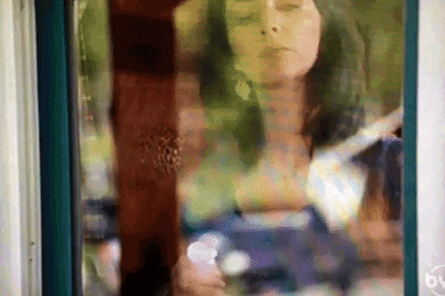 a painting of a woman looking out a window with a blurry background .