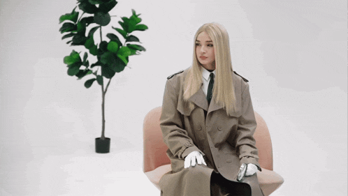 a woman in a trench coat sits in a chair with the words shut up you dirty sock below her