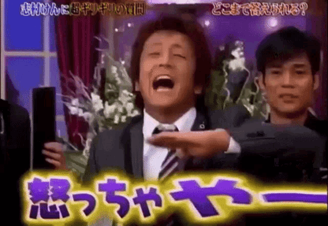 a man in a suit and tie is laughing in front of a sign that says ' angry ' on it