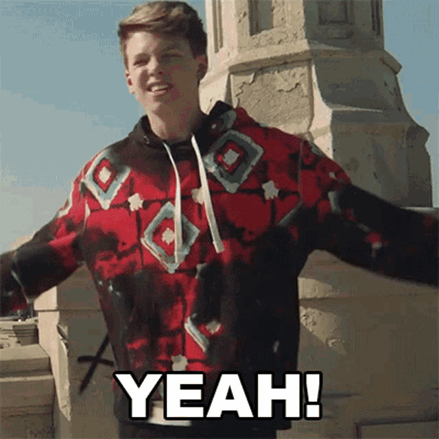 a young man in a red and black hoodie says yeah !