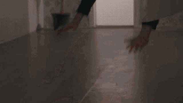a person is standing on a wooden floor with their hands on the floor .