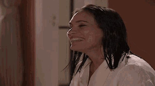 a woman with wet hair wearing a white robe smiles