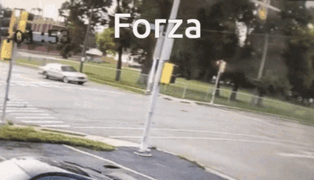 a white car is driving down a street with the word forza written on the pole