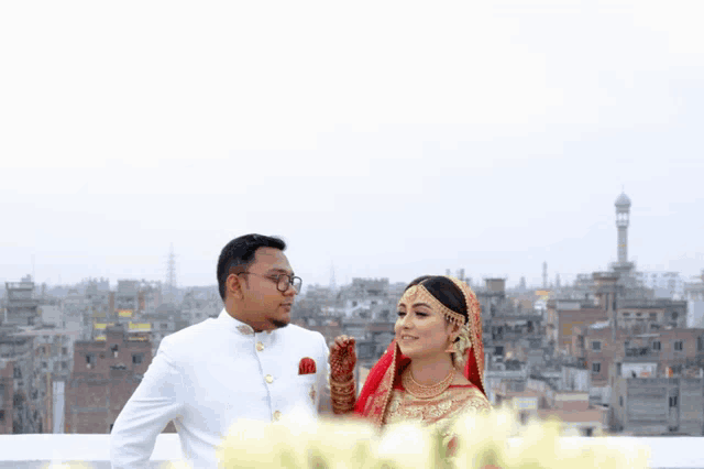 a bride and groom pose for a picture on a rooftop